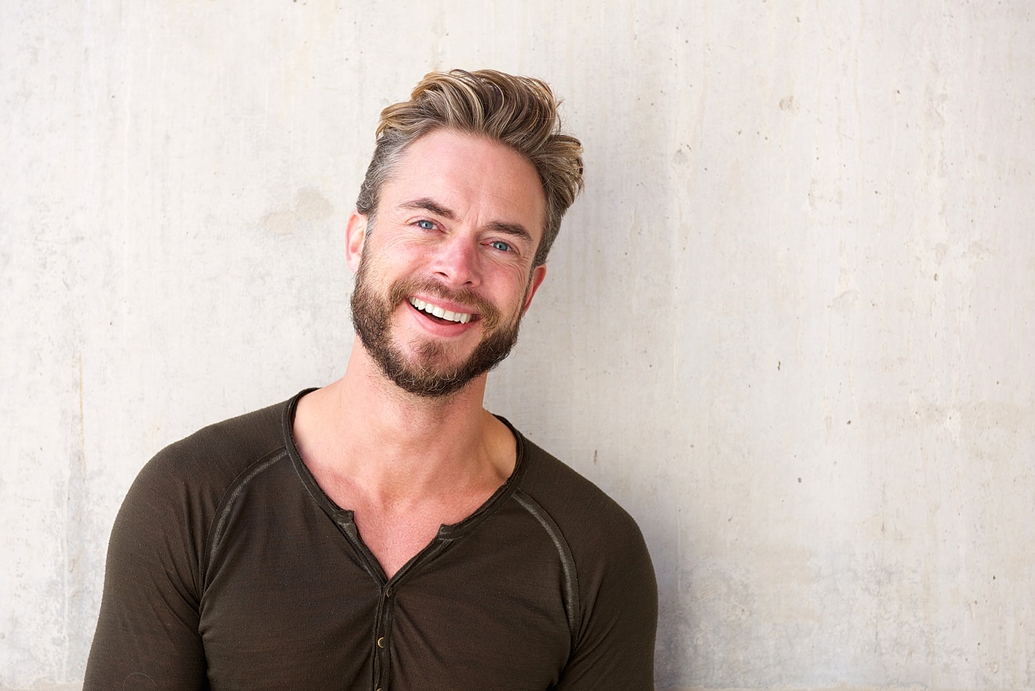 Beverly Hills plastic surgery model with beard against a concrete wall.